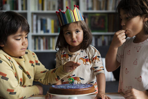 Porträt eines kleinen Mädchens, das seinen Geburtstag mit seinen älteren Brüdern zu Hause feiert - VABF03023
