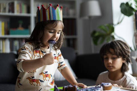 Porträt eines kleinen Mädchens, das einen Geburtstagskuchen isst, lizenzfreies Stockfoto