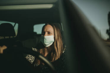 Mittlere erwachsene Frau mit Schutzmaske im Auto - DMGF00094