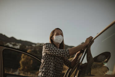 Mid adult woman with protective mask at car - DMGF00101