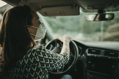 Mittlere erwachsene Frau mit Schutzmaske im Auto, lizenzfreies Stockfoto