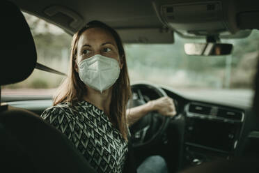 Mid adult woman with protective mask in car - DMGF00108