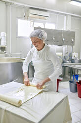 Käseproduktion, Arbeiterin rollt Käse, gerollter Schichtkäse - ZEDF03442