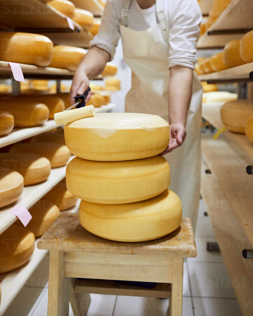 Closeup of a man slicing a Parmigiano Reggiano cheese wheel Stock
