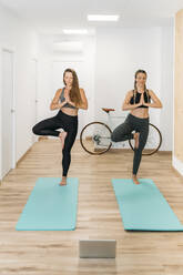 Zwei sportliche Frauen bei einem Online-Yogakurs im Fitnessstudio - MPPF00884