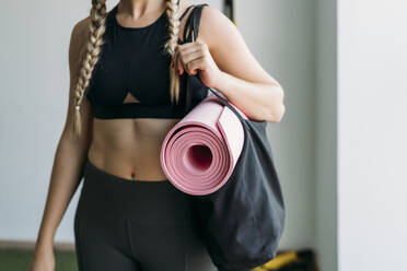 Sporty woman carrying bag with gym mat at health club - MPPF00941