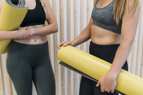 Zwei sportliche Frauen halten Turnmatten im Fitnessstudio - MPPF00954