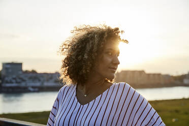 Portrait of smiling woman looking sideways in the evening light - MJFKF00358
