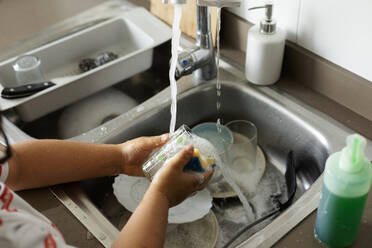 Junge wäscht zu Hause Geschirr - VABF03032