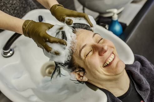 Frau im Friseursalon wäscht sich die Haare mit Bürsten - JATF01203