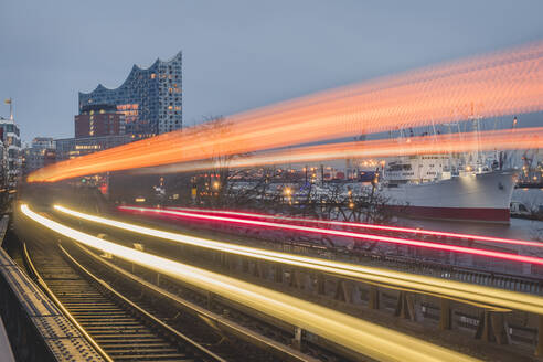 Germany, Hamburg, Train light trails along elevated railway track at dusk - KEBF01528