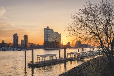Germany, Hamburg, Empty harbor on bank of Elbe river at sunrise with Elbphilharmonie in background - KEBF01533