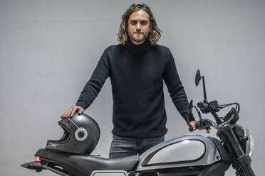 Young man standing on motorcycle with helmet - DLTSF00731