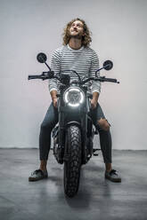 Junger Mann auf Motorrad sitzend - DLTSF00732