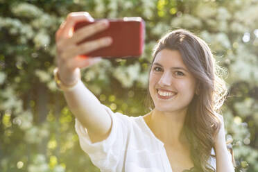 Lächelnde Frau macht ein Selfie im Freien - WPEF03007