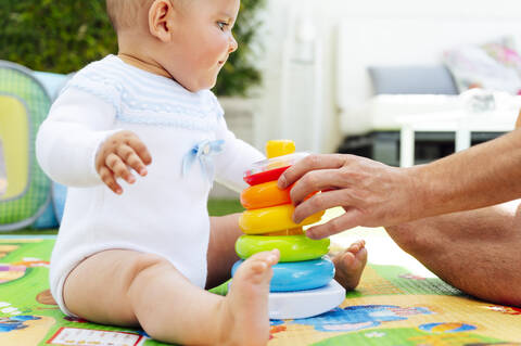 Abgeschnittene Hände des Vaters, der Spielzeug ordnet, während er mit seinem Sohn zu Hause spielt, lizenzfreies Stockfoto