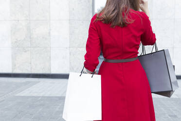 Young woman carrying shopping bags while standing on street in city - JPTF00521