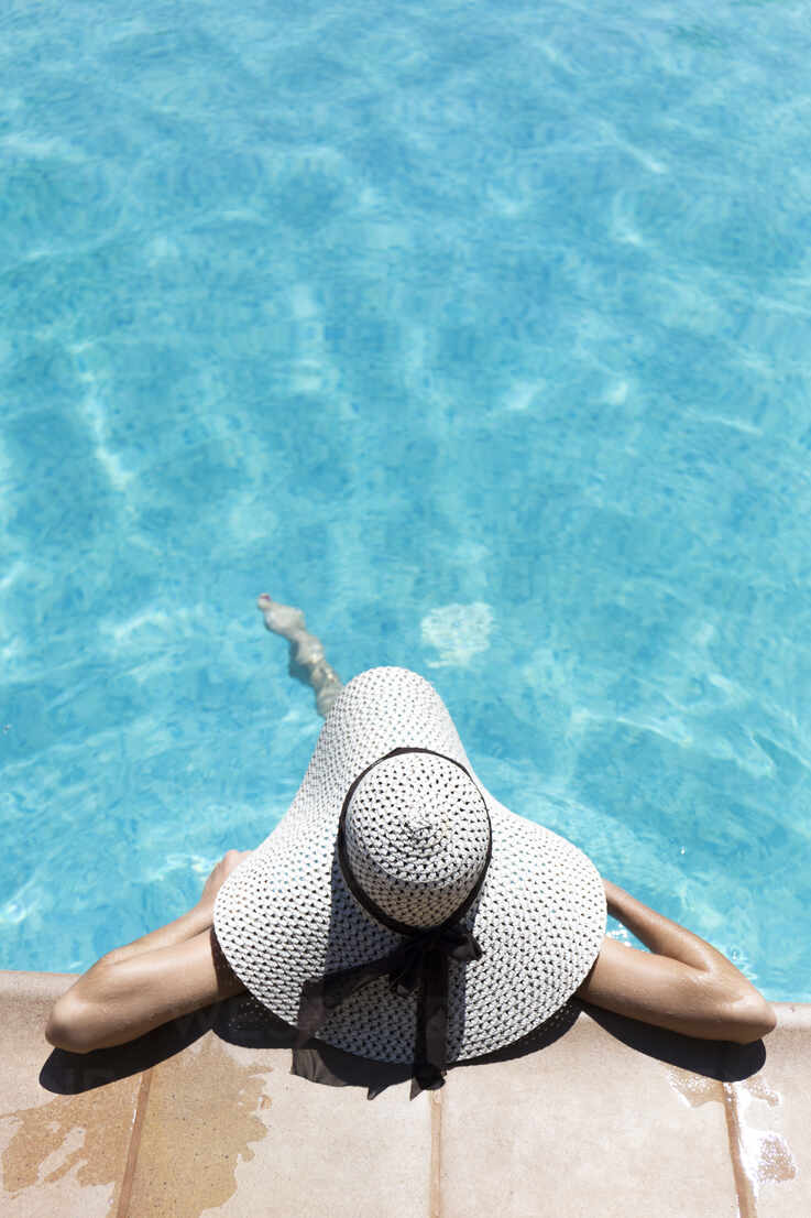 Young woman wearing hat swimming in pool at tourist resort during sunny day  stock photo