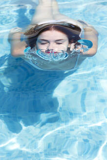 Nahaufnahme einer jungen Frau mit geschlossenen Augen beim Schwimmen im Pool eines Ferienortes - JPTF00552