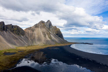 Aerial view of a mountain on the shore of the bay on cloudy day in Iceland - AAEF09114