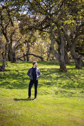 Full body portrait of young man casually dressed outdoors with trees - CAVF84527