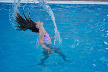 Mädchen im Schwimmbad mit dem Kopf, der das Wasser zurückzieht - CAVF84607