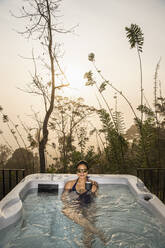 Woman enjoying a bath in a hot tub in the Sri Lankan highlands - CAVF84874