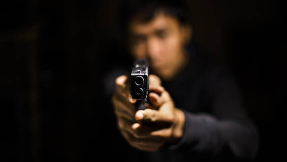 Close-Up Of Man Holding Gun In Darkroom - EYF05091