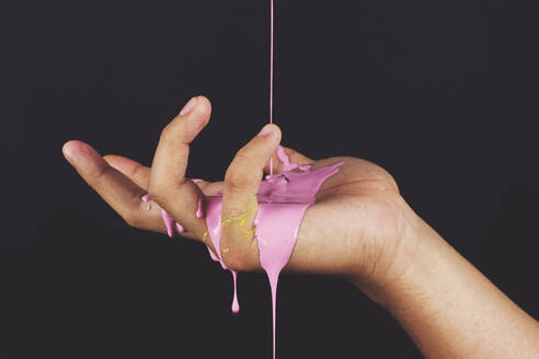 Close-Up Of Pink Color Being Poured On Hand Over Black Background - EYF05095