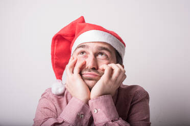 Trauriger Mann mit Weihnachtsmannmütze vor weißem Hintergrund - EYF05122