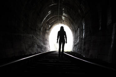 Rear View Of Woman Standing On Railroad Track In Tunnel - EYF05127