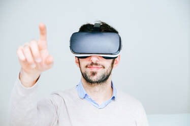 Porträt eines Mannes, der eine Virtual-Reality-Brille vor weißem Hintergrund trägt - EYF05140
