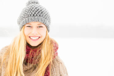 Portrait Of Smiling Young Woman In Snow Against White Background - EYF05182