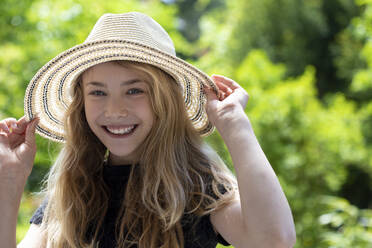 Close-up of carefree girl wearing hat against trees in park - JFEF00948