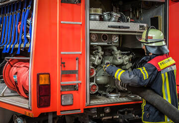 Fireman carrying fire hose reel, Darlington, UK stock photo