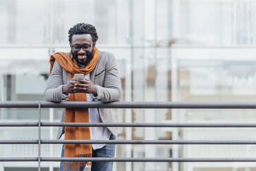 Man Using Mobile Phone While Standing At Railing - EYF05306