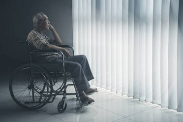 Seitenansicht eines älteren Mannes, der auf einem Rollstuhl sitzt - EYF05317