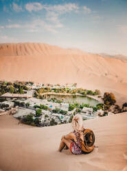 Frau sitzend in der Wüste gegen den Himmel - EYF05328