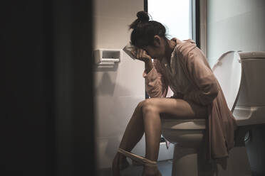 Woman With Stomach Ache Sitting On Toilet Bowl - EYF05383