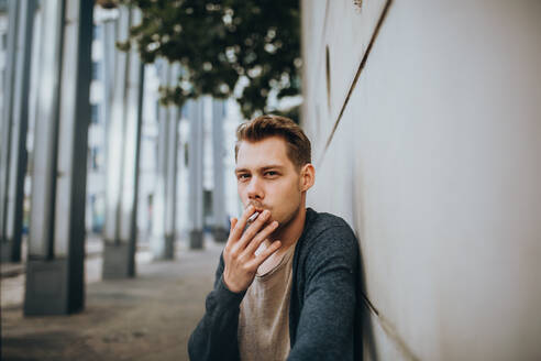 Junger Mann raucht Zigarette im Freien - EYF05401