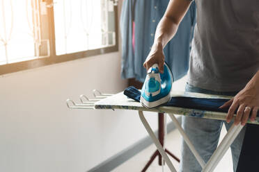 Midsection Of Man Ironing Clothes At Home - EYF05410