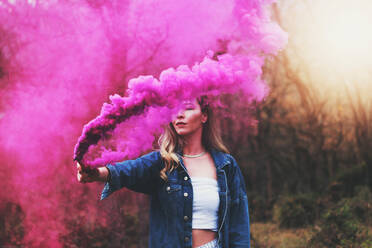 Young Woman Holding Distress Flare While Standing At Forest - EYF05413