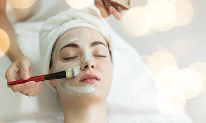 Cropped Hands Of Beautician Applying Facial Mask On Female Customer In Spa - EYF05424