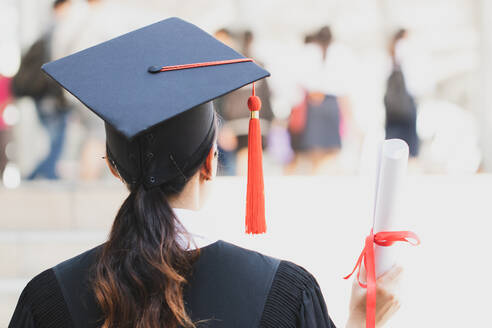 Rear View Of Young Woman Wearing Graduation Gown Standing im Freien - EYF05430