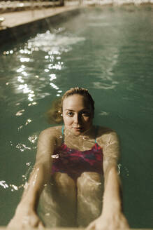 Mid adult woman swimming in hot pool at tourist resort during night - MRRF00085
