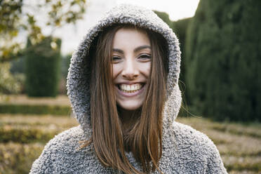 Close-up of cheerful beautiful woman wearing hood in park during winter - ABZF03200