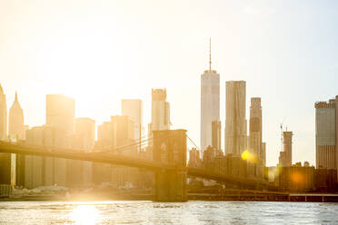 USA, New York, New York City, Untergehende Sonne, die die Brooklyn Bridge und die Skyline von Manhattan beleuchtet - PUF01898