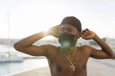 Black man with beanie putting on face mask - EGAF00171