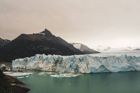 Argentina, Iceberg floating near mountainous coastline - UUF20650