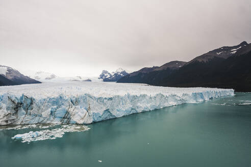 Argentina, Iceberg floating near mountainous coastline - UUF20651
